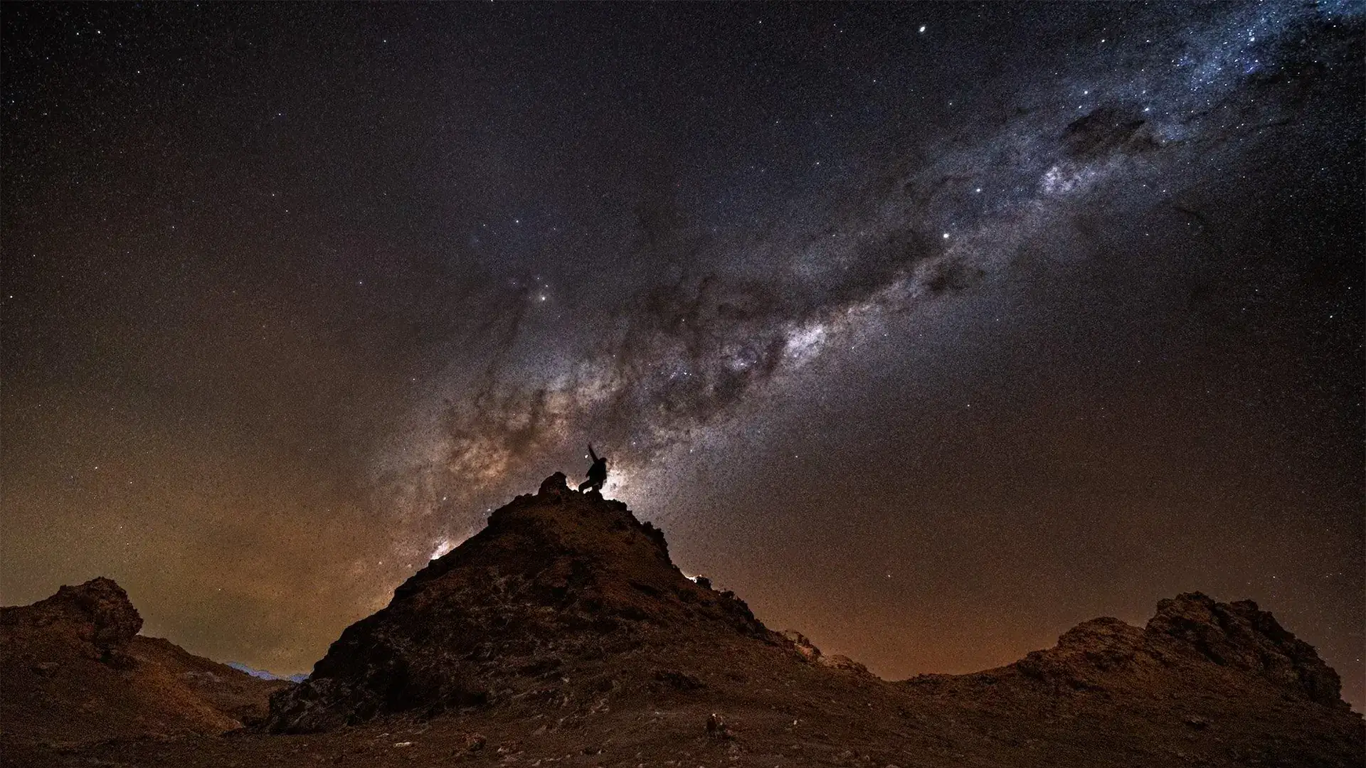 The Milky Way over a dark mountain landscape at night